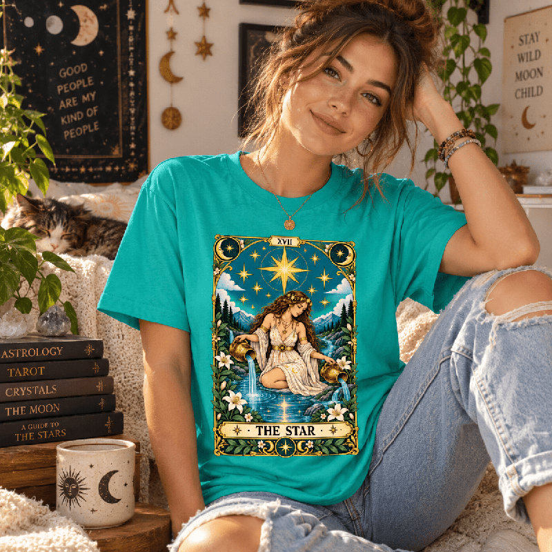 Woman seated among celestial decor, wearing the Star Premium T-Shirt in heather sea green