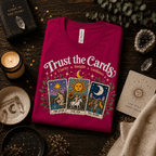 Trust The Cards Premium T-Shirt in berry, folded close-up styled with crystals and a candle