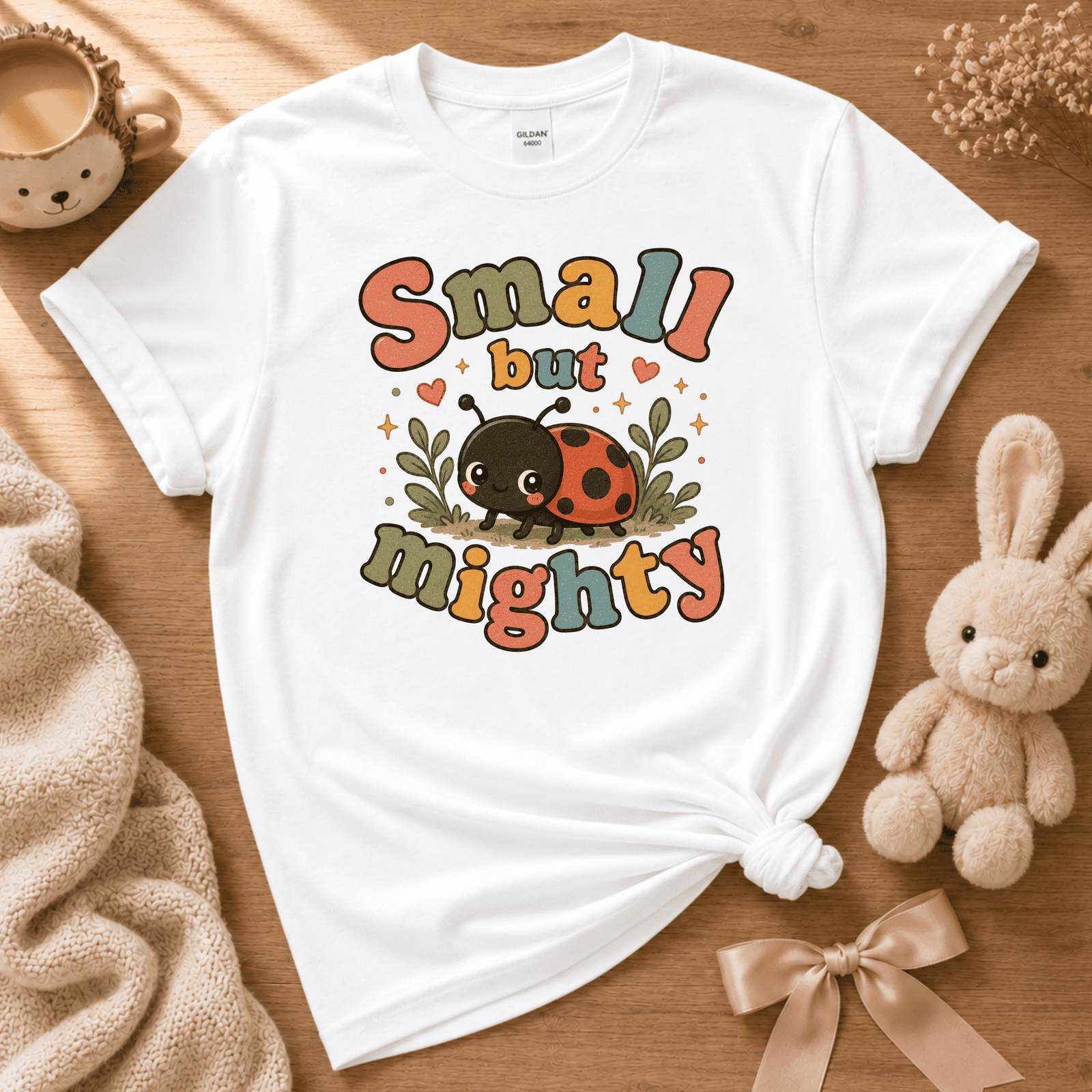 Small But Mighty cute animal graphic t-shirt displayed in a cozy flat lay in white.