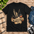 Winging It Premium T-Shirt in vintage black, flat lay with tattoo-style swallow bird graphic