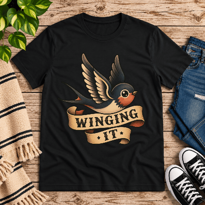 Winging It Premium T-Shirt in vintage black, flat lay with tattoo-style swallow bird graphic