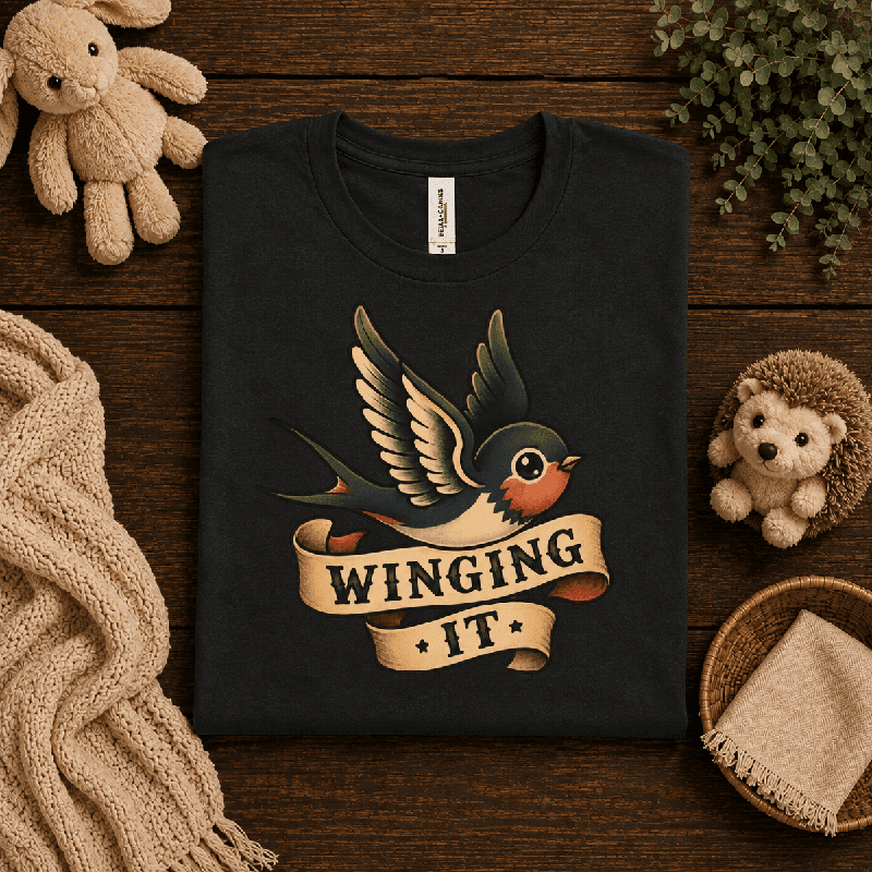 Winging It Premium T-Shirt in vintage black, folded close-up styled with plush toys